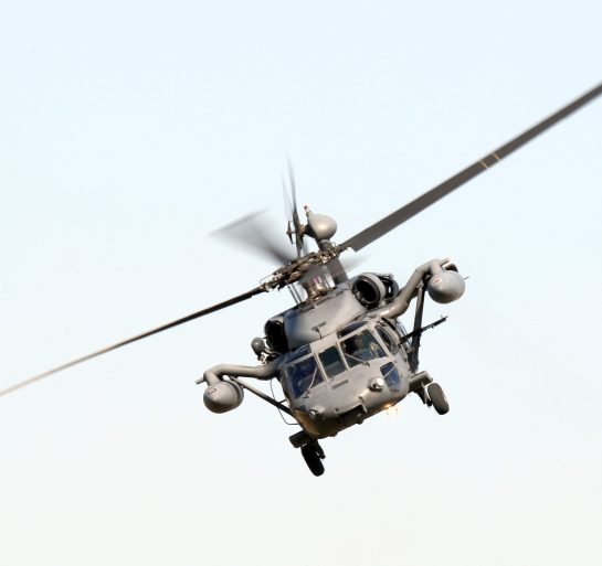 A low angle isolated shot of a military hawk maneuvring on a white background